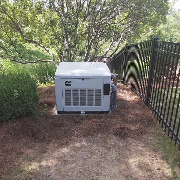 Standby generator installed beside a fence line