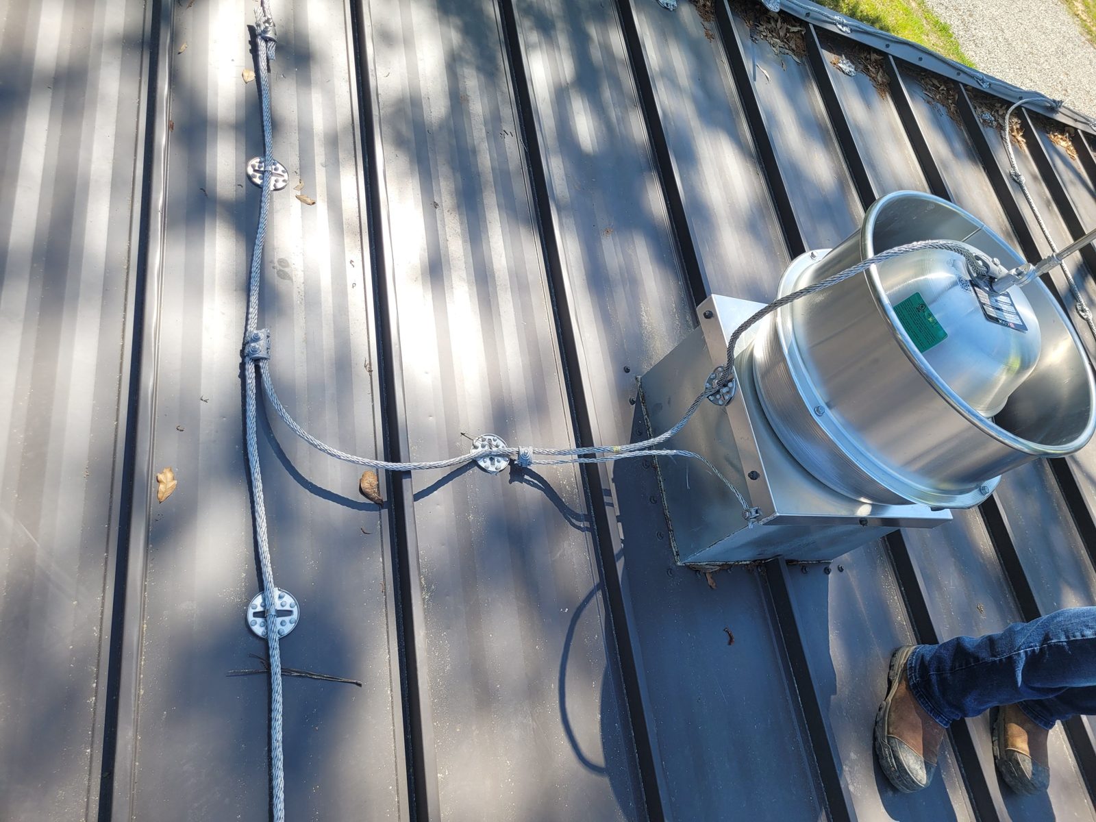 Rooftop lightning protection conductor bonded to a roof vent, installed by Ritch Electric